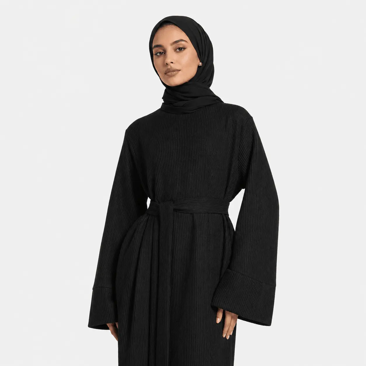 Woman wearing a black ribbed dress with a belt on a white background
