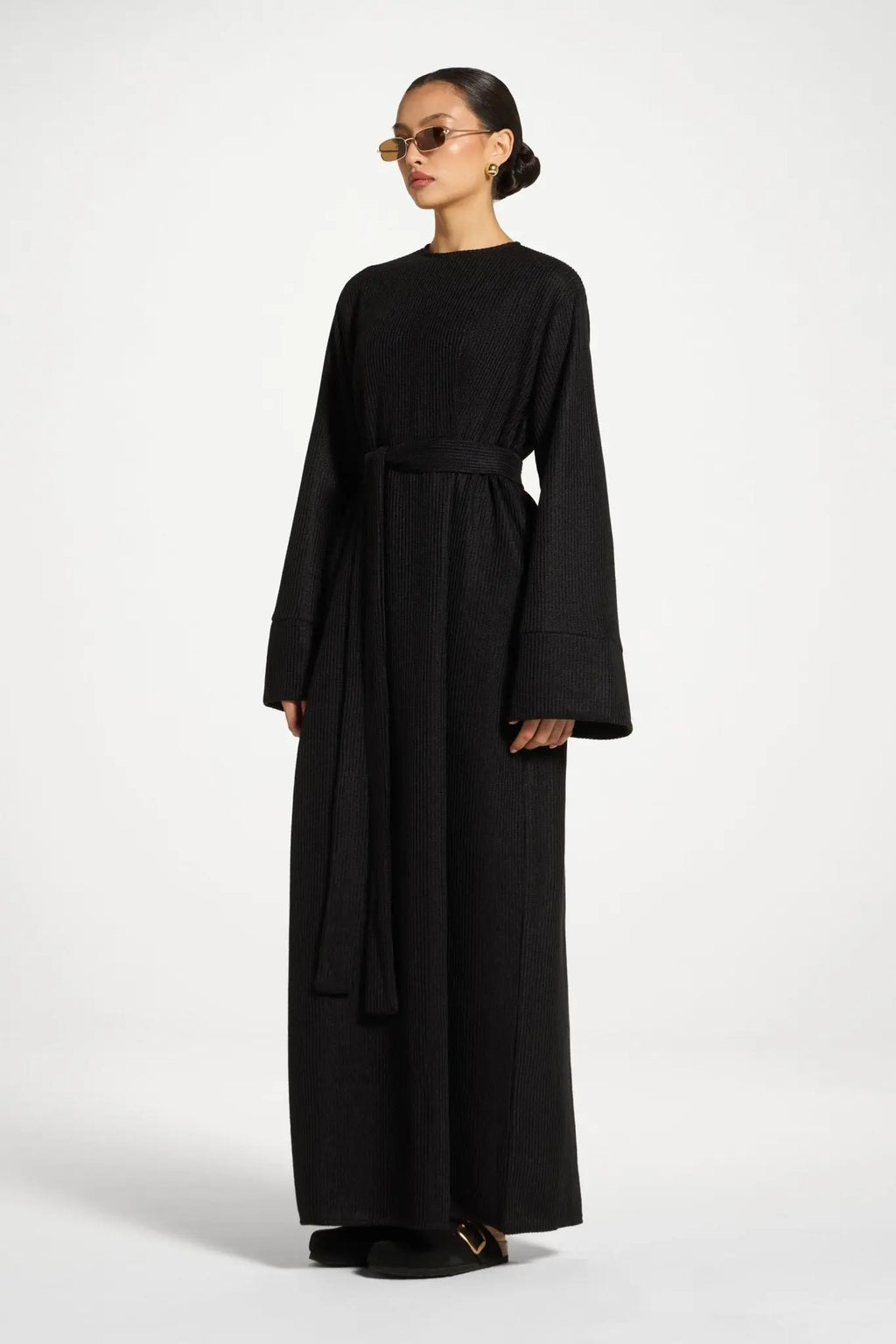Woman wearing a black long-sleeve dress on a white background