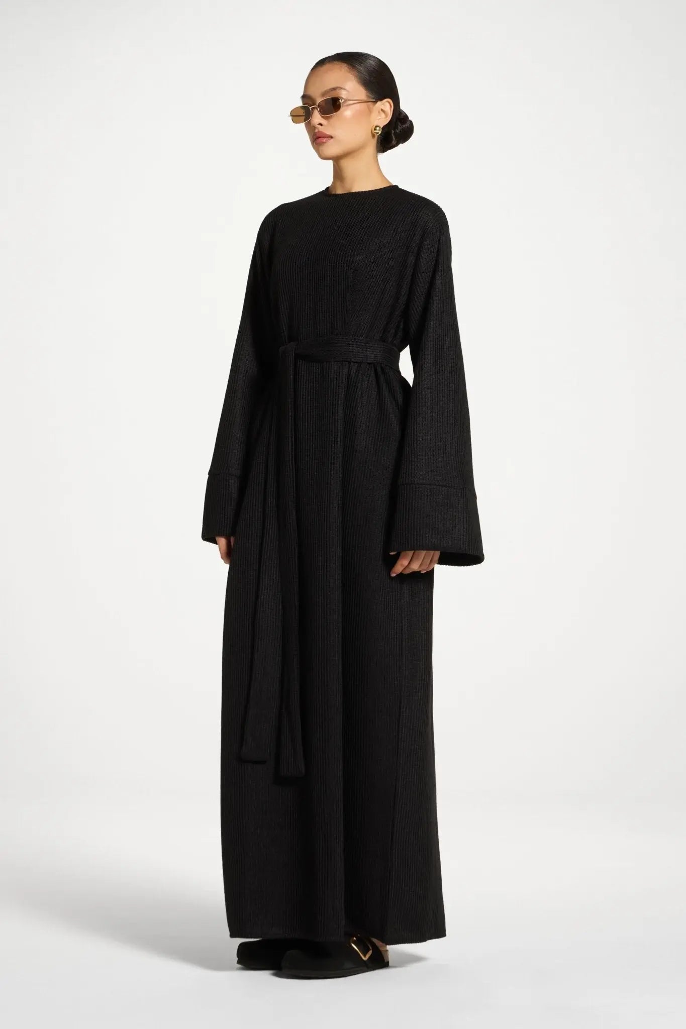 Woman wearing a black long-sleeve dress on a white background