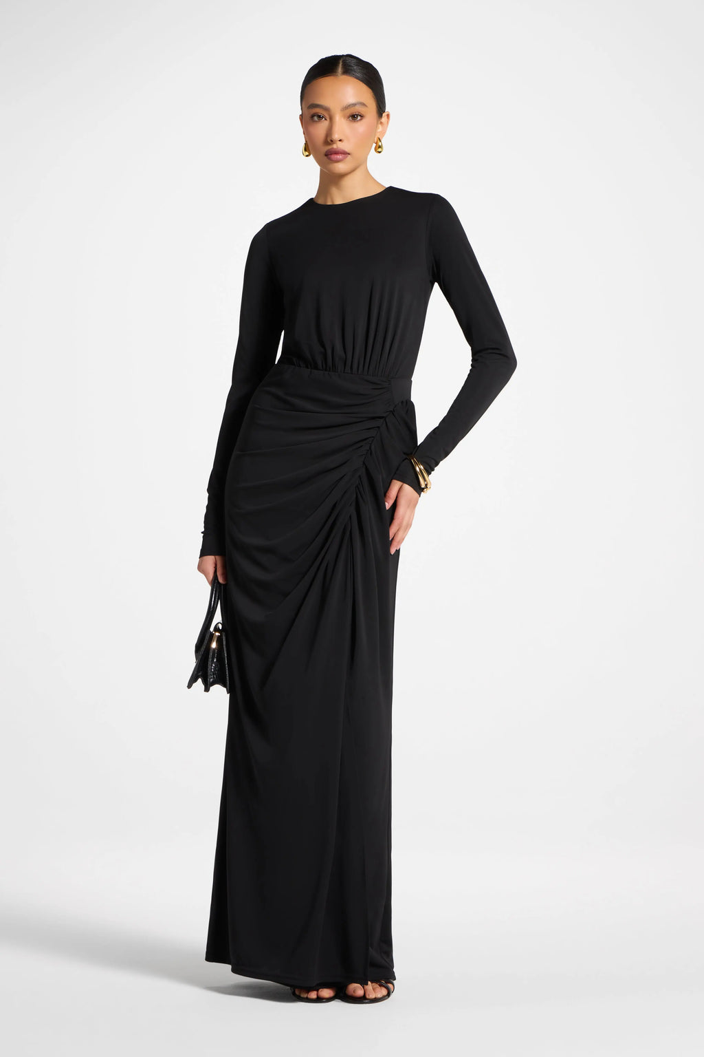 Woman wearing a black long-sleeve gown with a draped design on a white background
