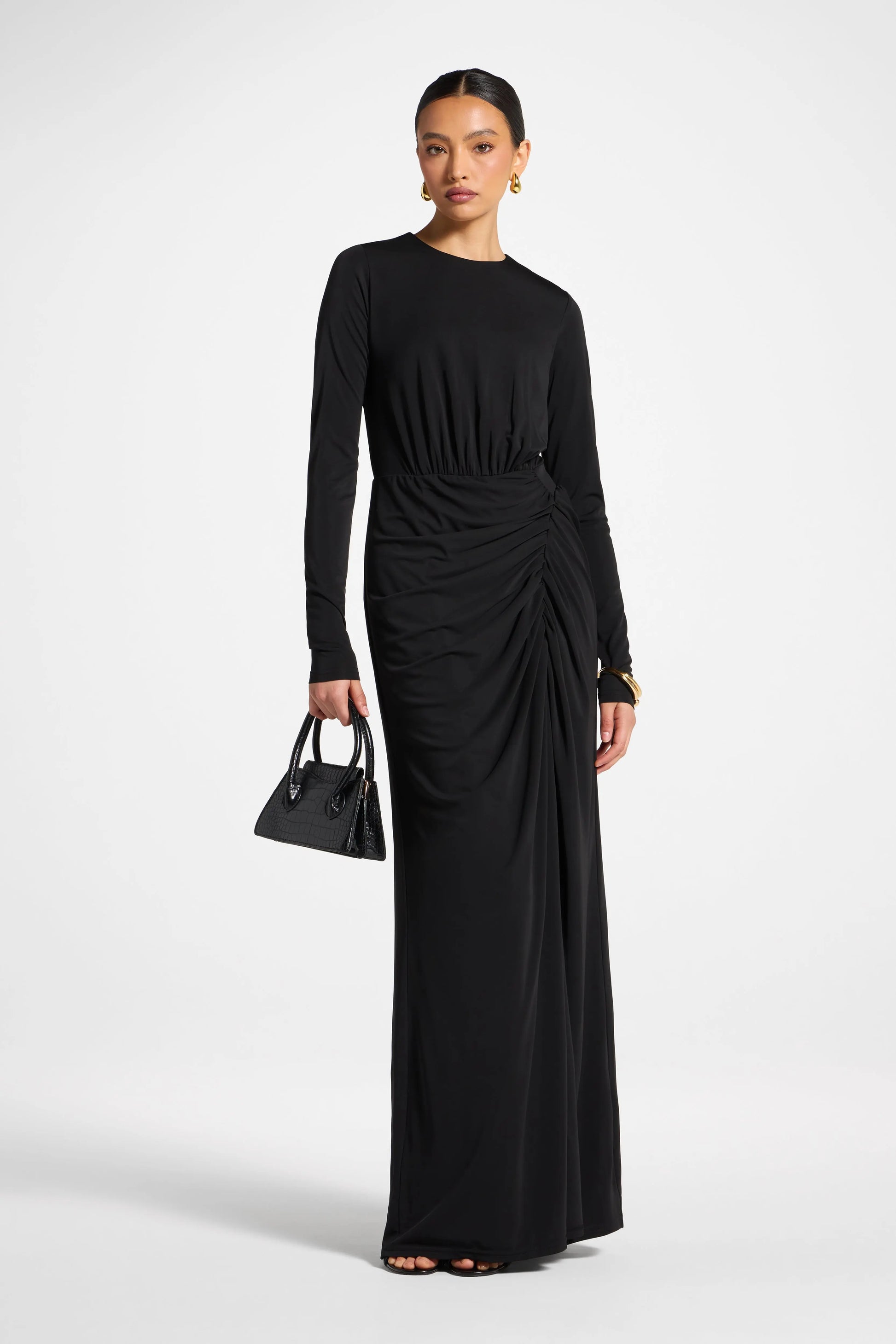 Woman wearing a black dress with a draped effect on a white background