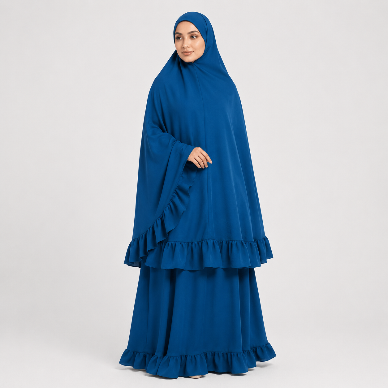 Woman wearing a blue dress with a matching hijab on a white background