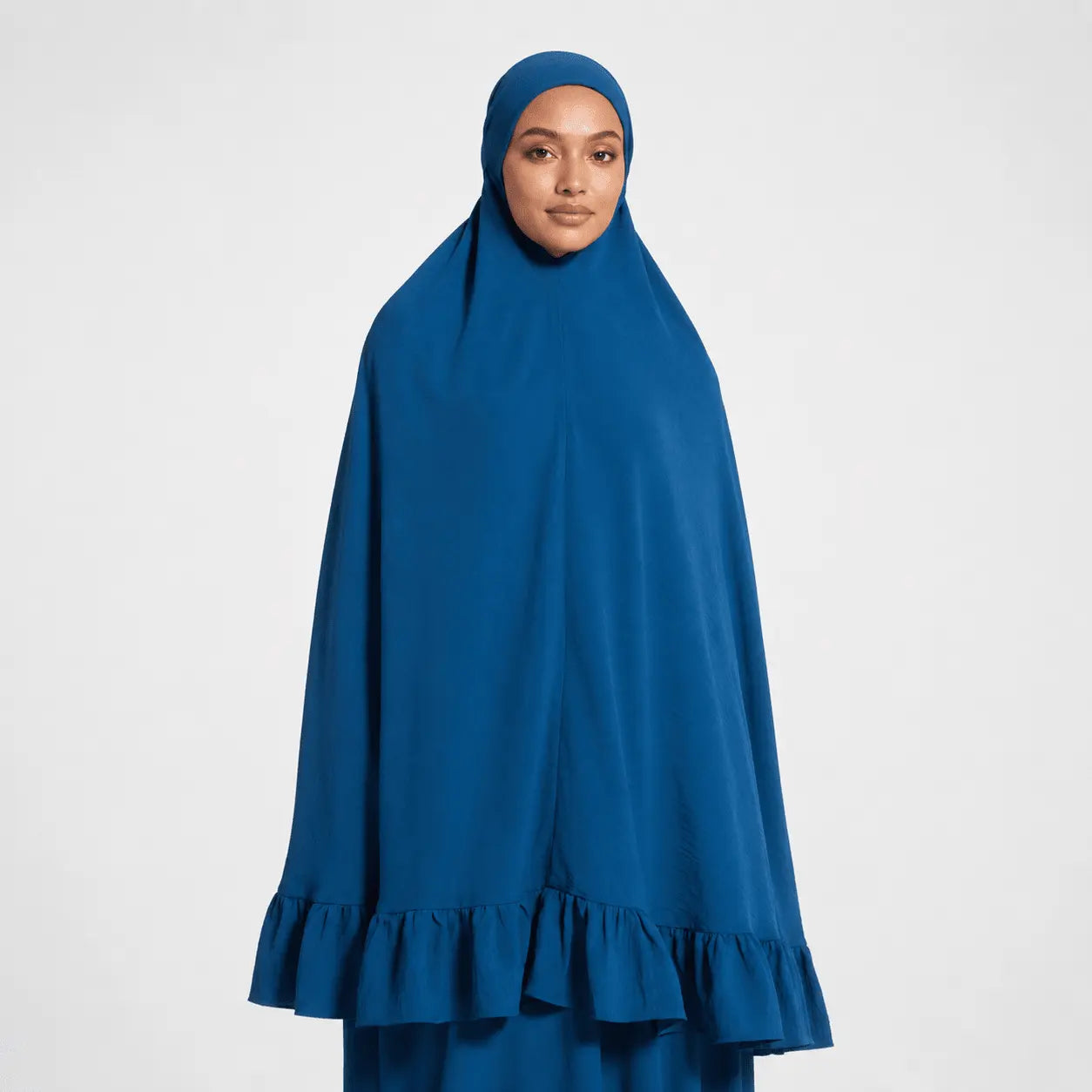 Woman wearing a blue hijab with ruffled bottom on a white background