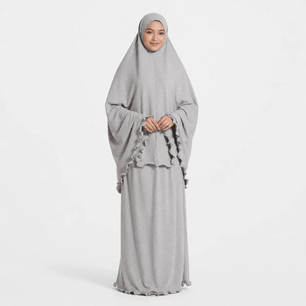 Woman wearing a gray dress with a matching hijab on a white background