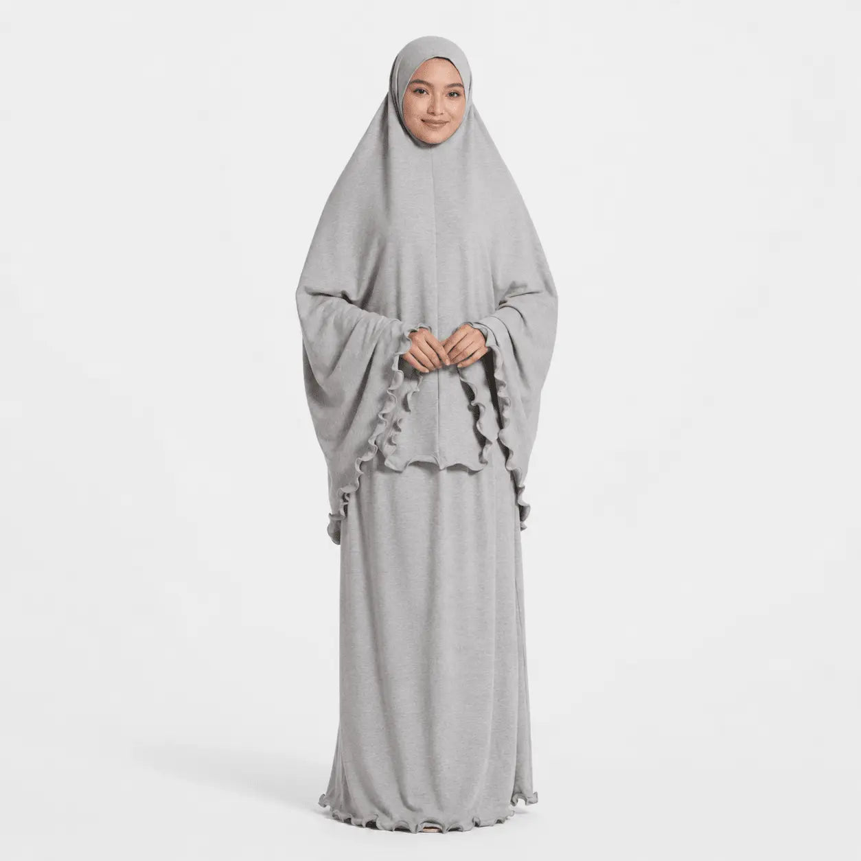 Woman wearing a gray dress with a matching hijab on a white background