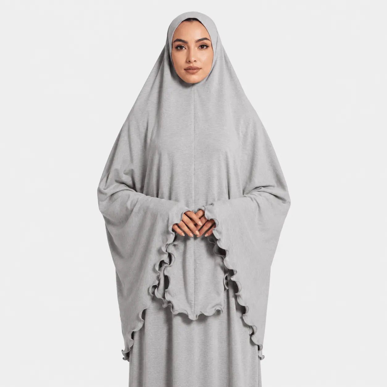 Woman wearing a gray abaya with ruffled sleeves on a light gray background