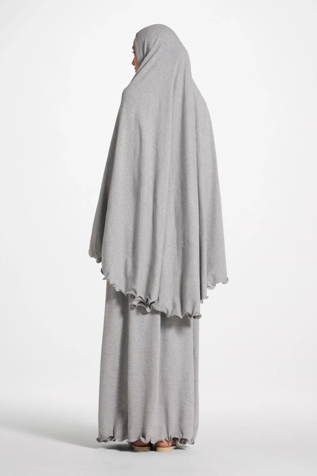 Person wearing a gray abaya on a white background