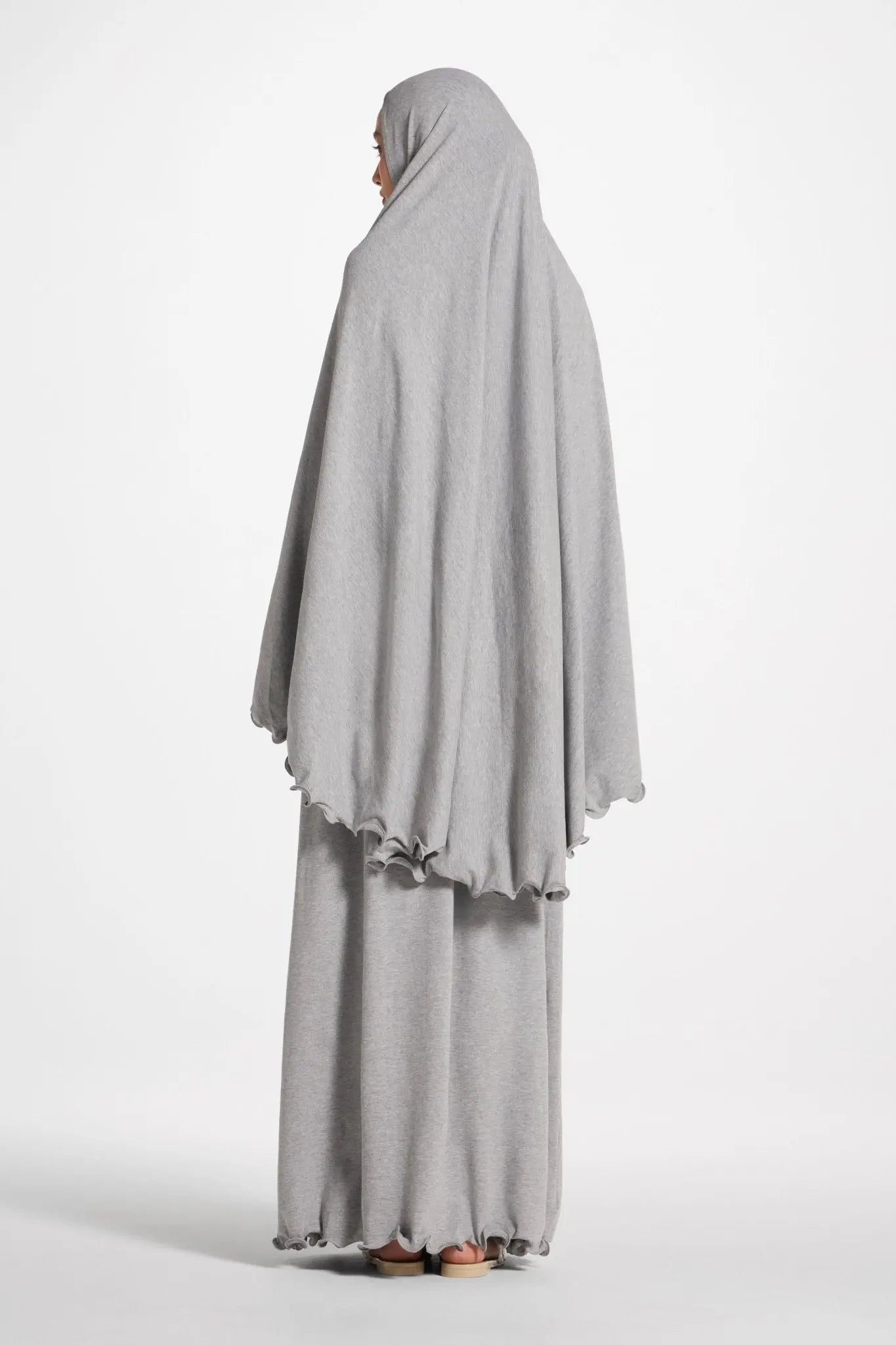 Person wearing a gray abaya on a white background