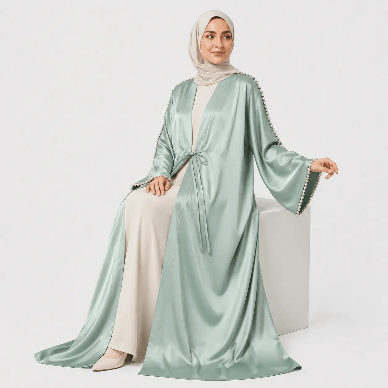 Woman wearing a light green abaya with white hijab on a white background