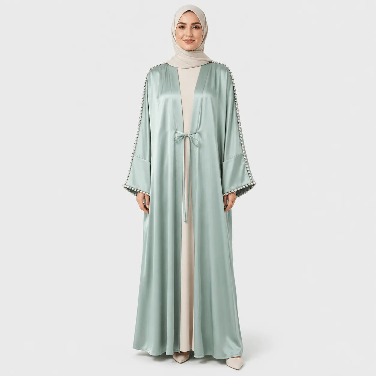 Woman wearing a light green abaya with decorative trim on a white background