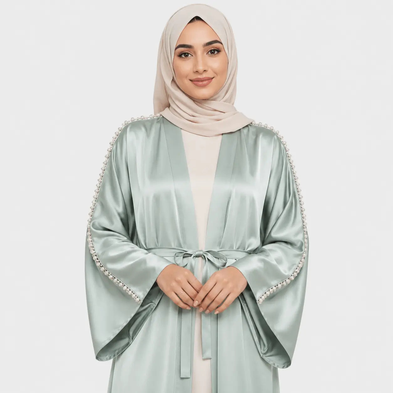 Woman wearing a light green abaya with embellishments on a white background