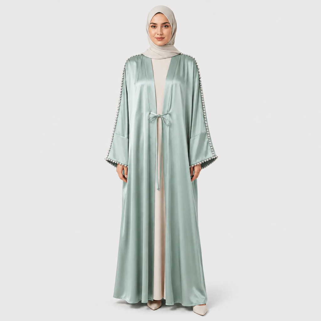Woman wearing a light green abaya with decorative trim on a white background