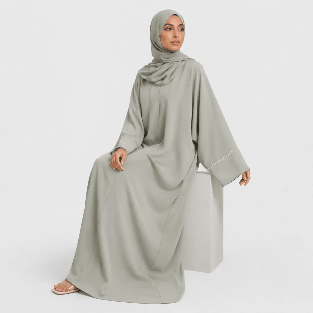 Woman wearing a light gray abaya on a white background