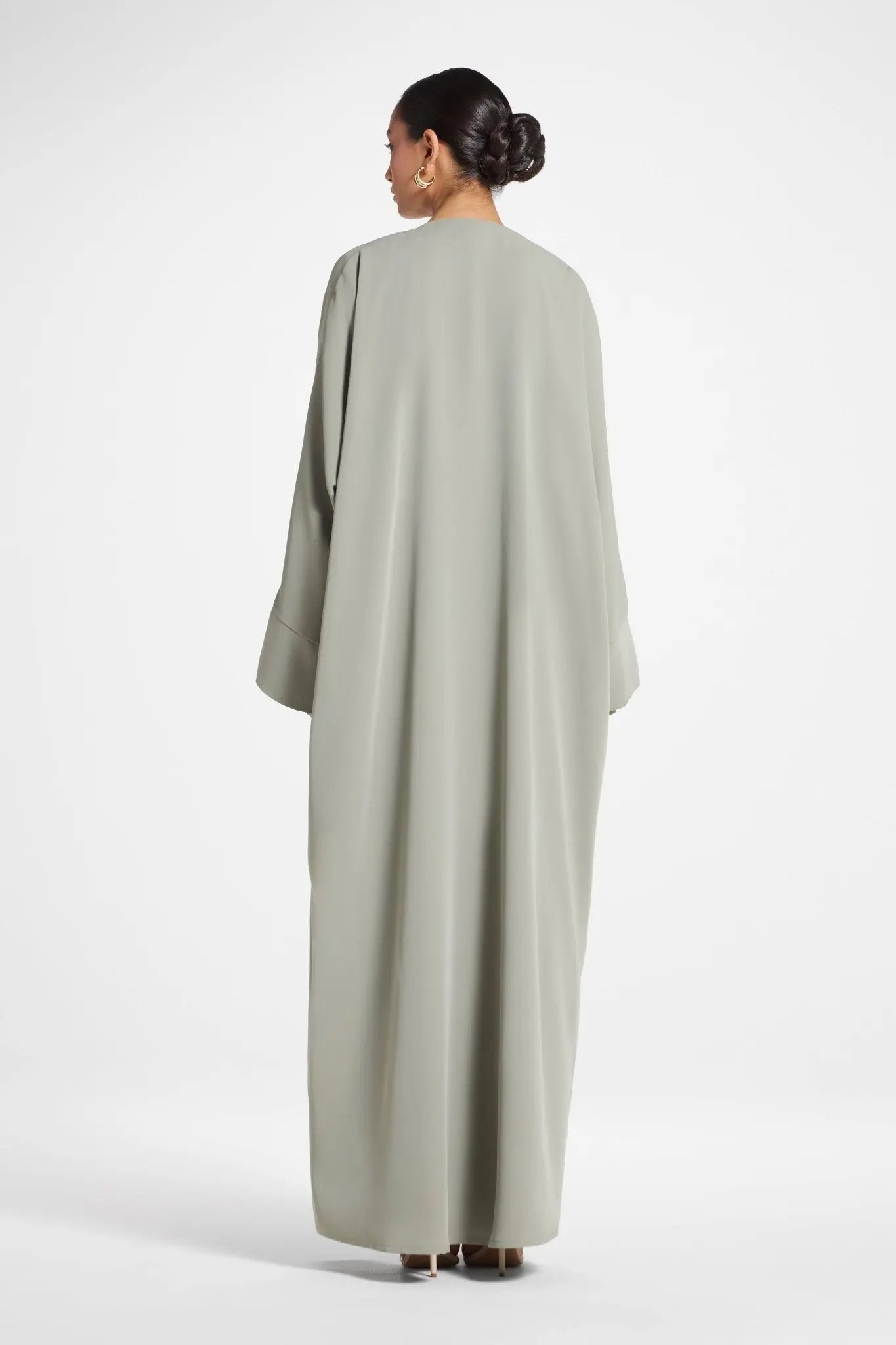 Woman wearing a long, light gray dress against a white background