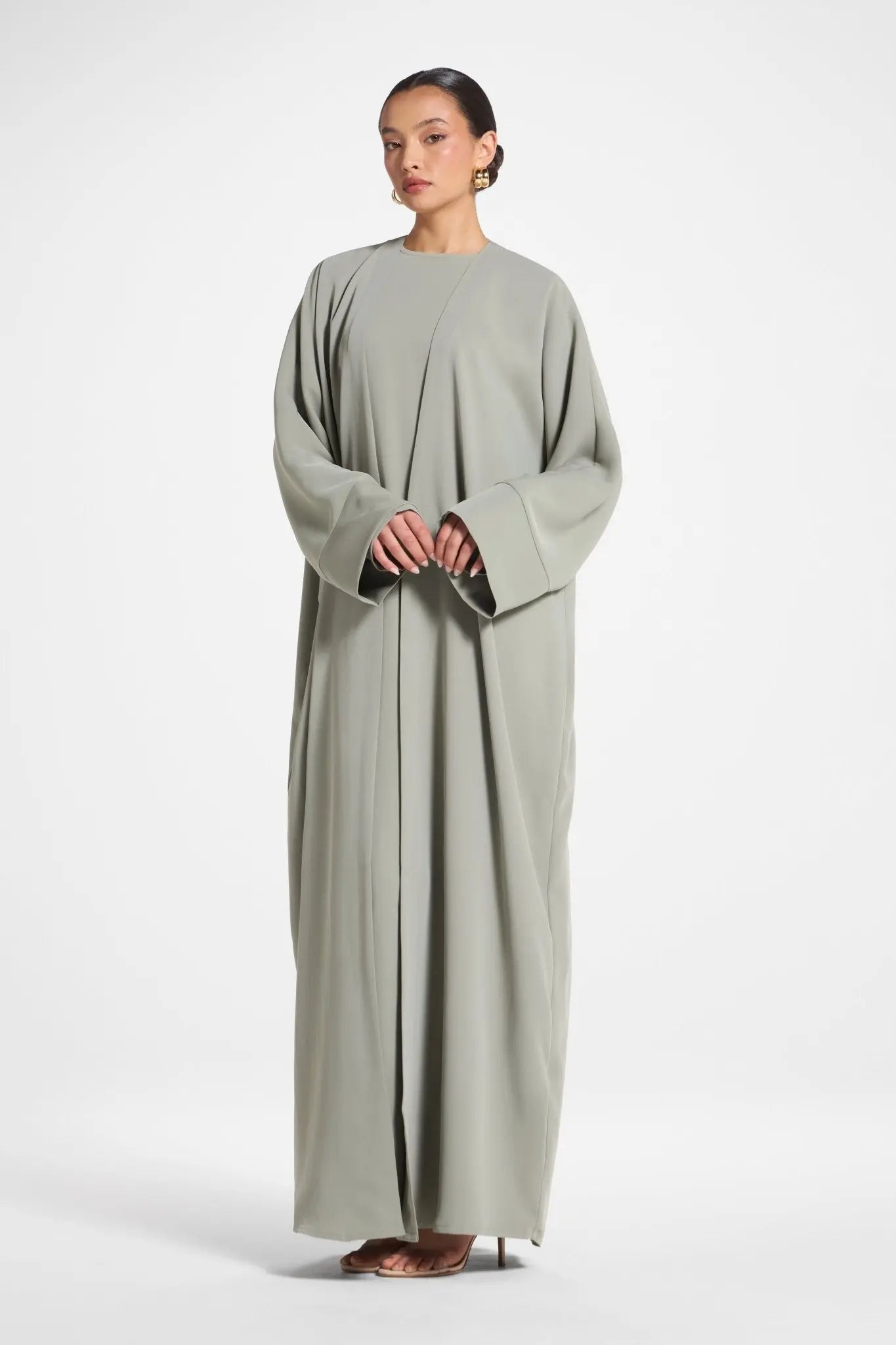 Woman wearing a long, light gray dress on a white background