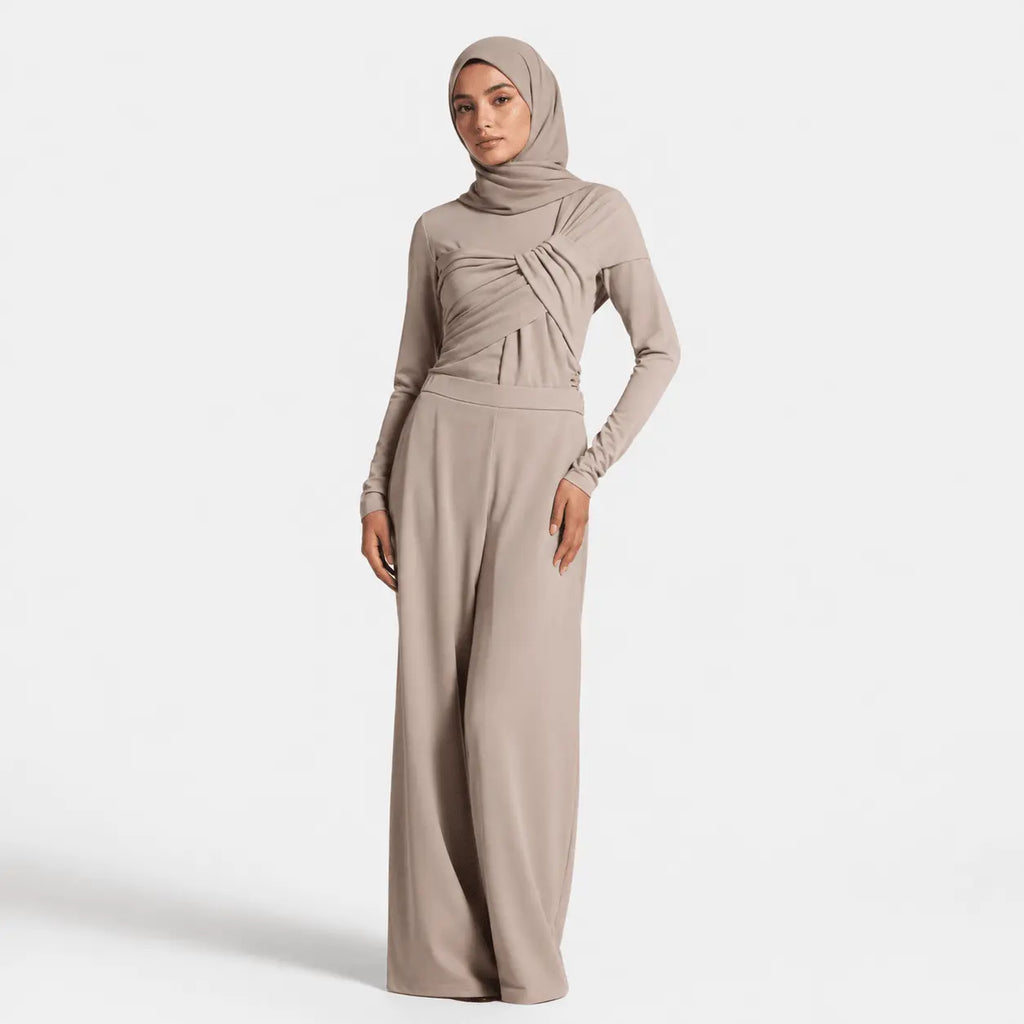 Woman wearing a beige hijab and matching outfit on a white background