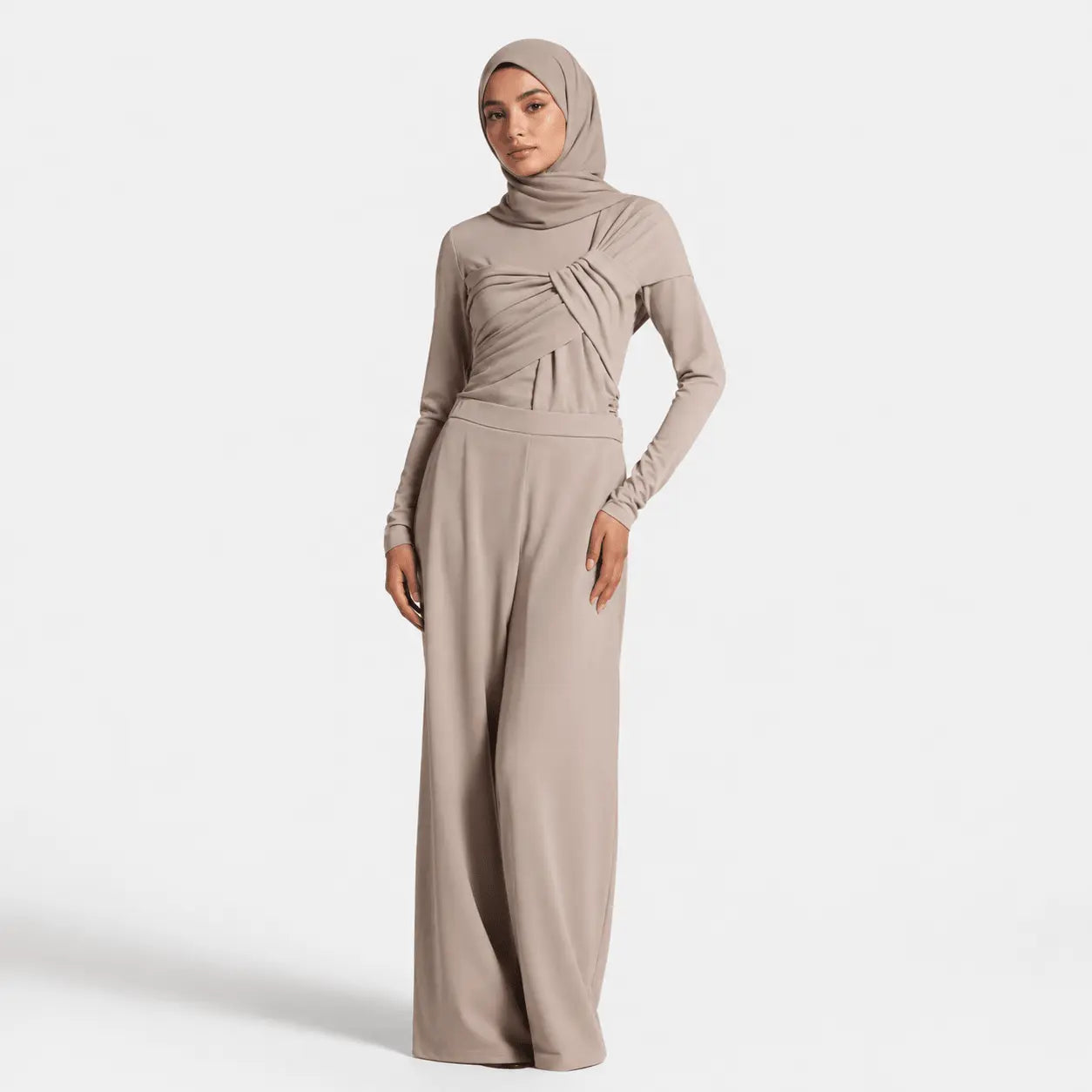 Woman wearing a beige hijab and matching outfit on a white background