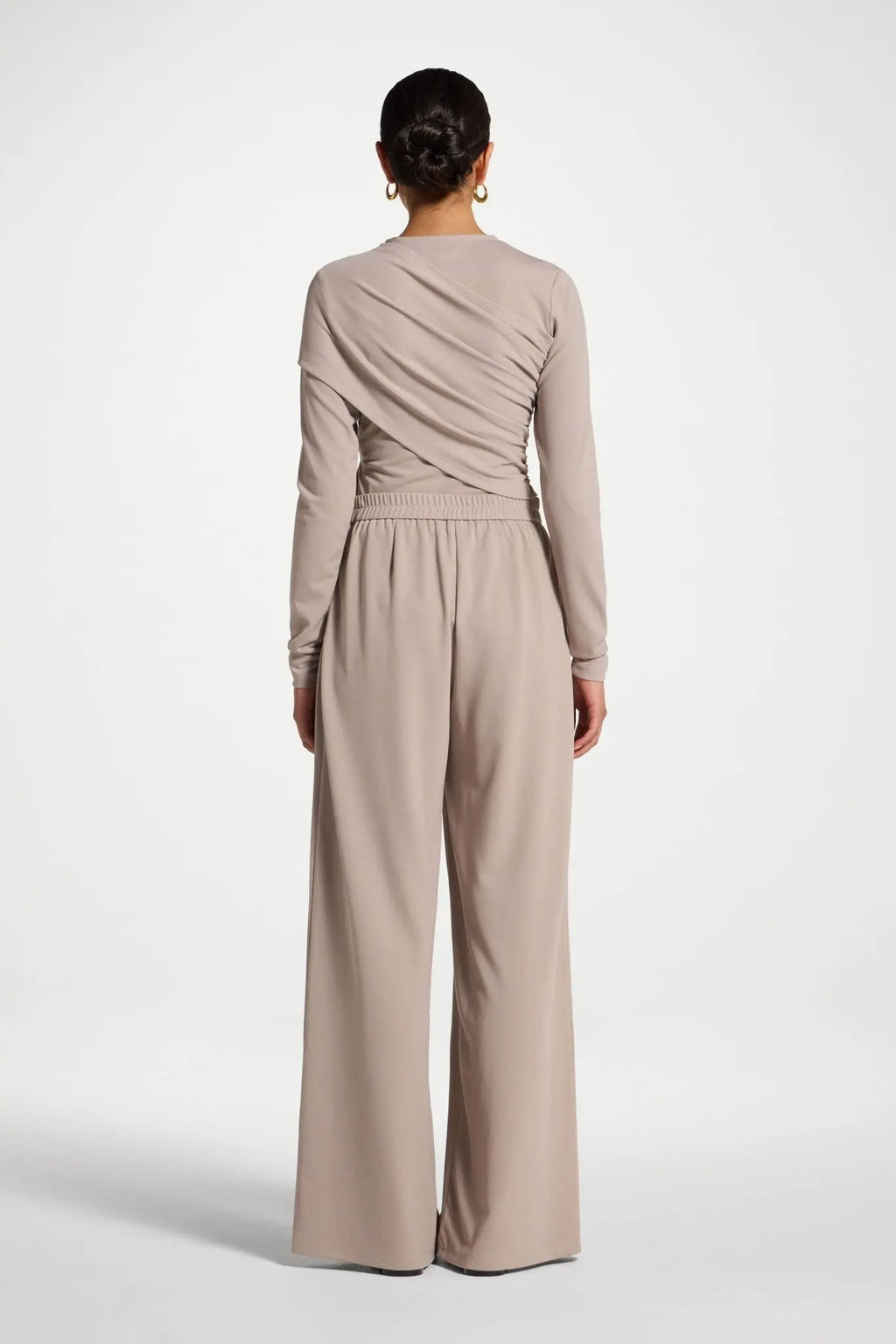 Person wearing a beige jumpsuit on a white background