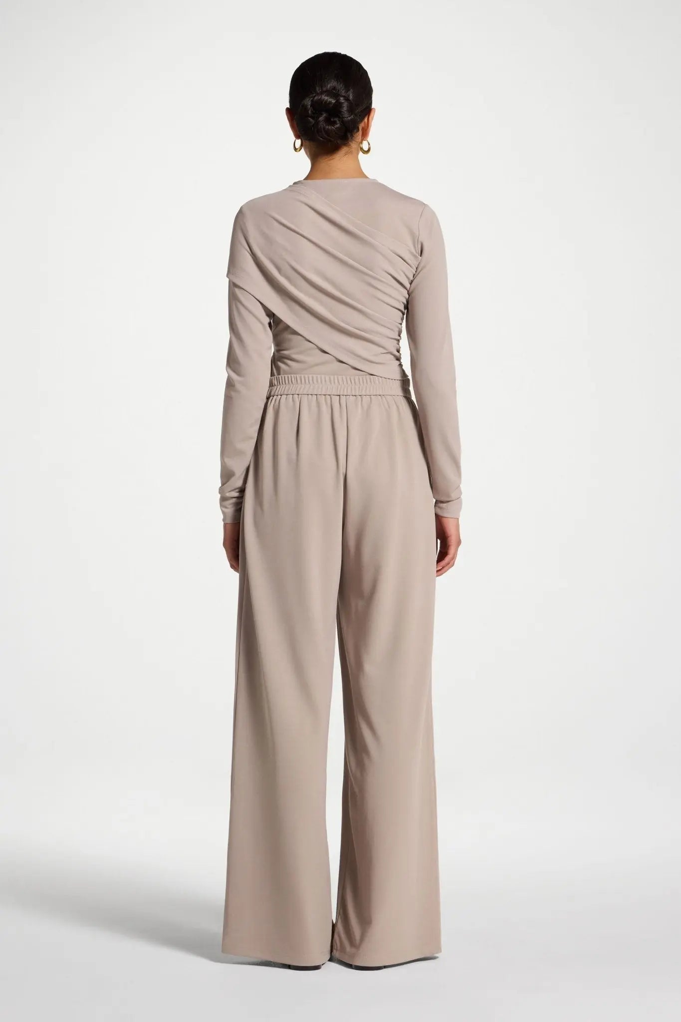 Person wearing a beige jumpsuit on a white background