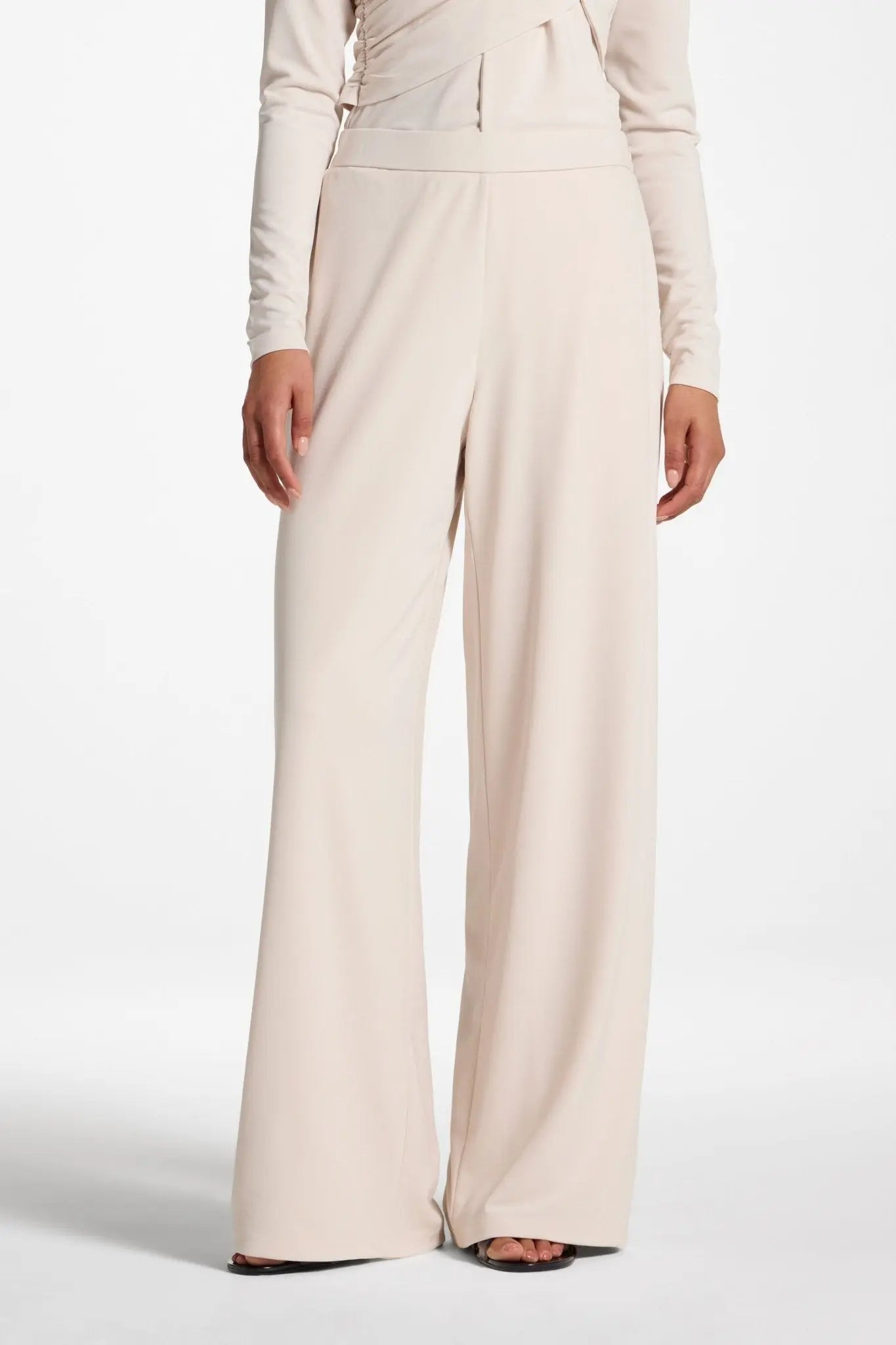 Beige wide-leg pants worn by a person on a white background