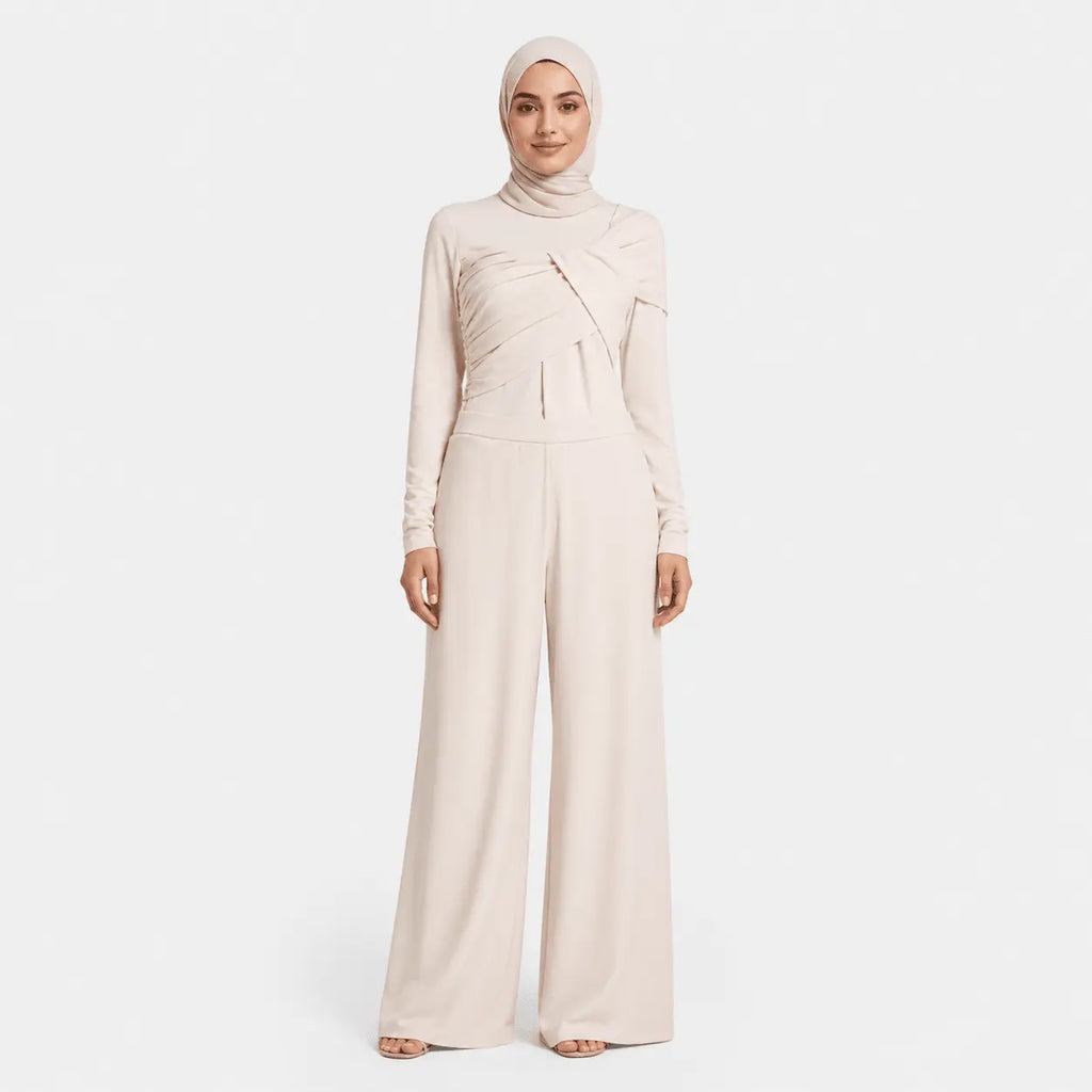 Woman wearing a beige jumpsuit and hijab on a white background