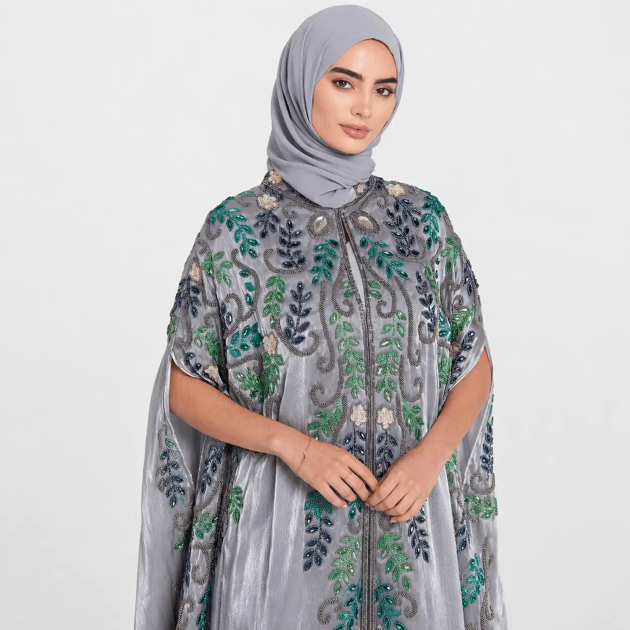 Woman wearing a gray embroidered dress with floral patterns on a white background