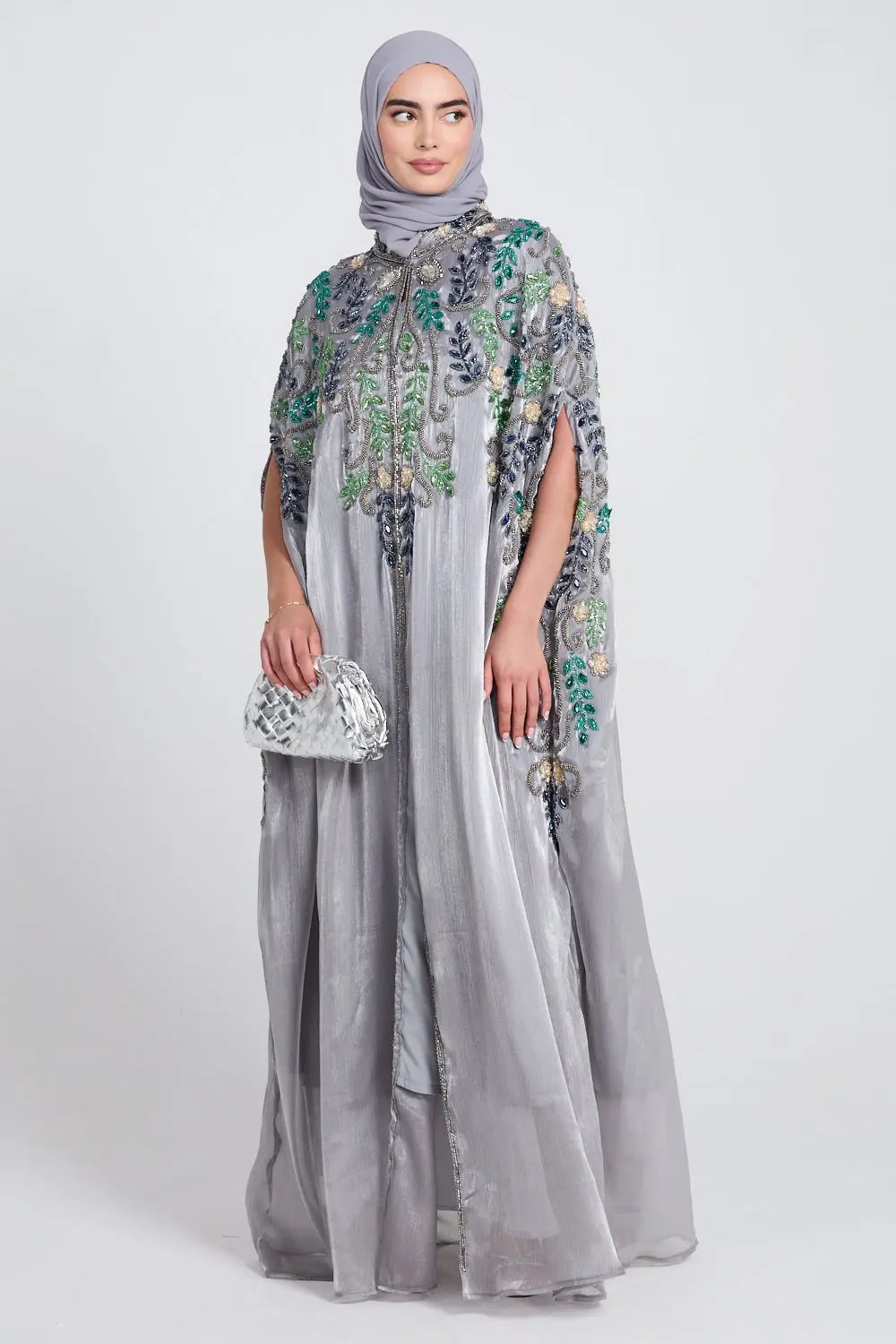 Woman wearing a gray embroidered dress with a matching hijab on a white background