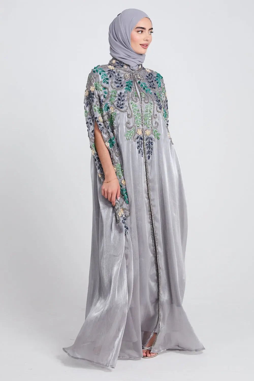 Woman wearing a gray embroidered dress with a hijab on a white background