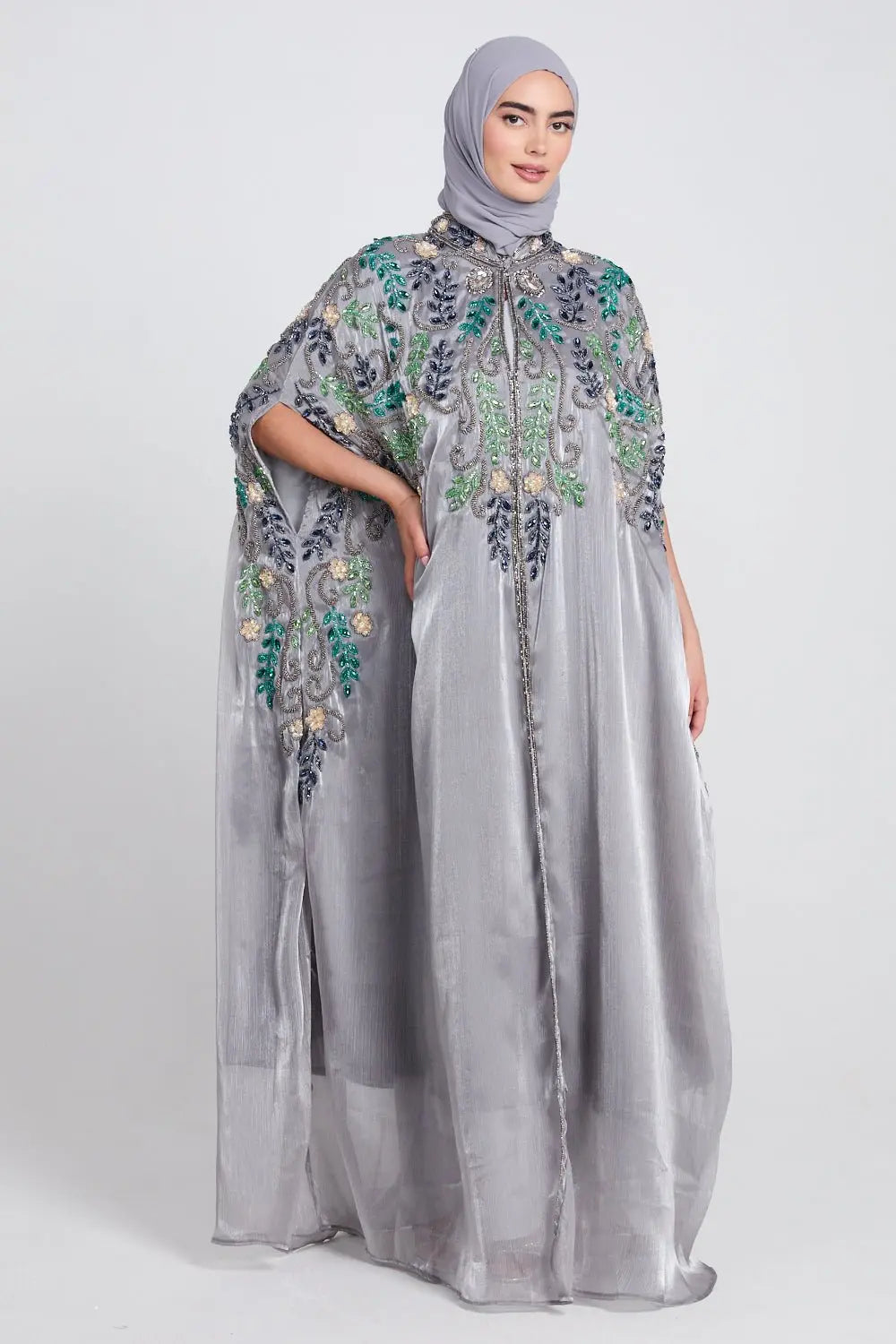 Woman wearing a gray embroidered dress with a matching hijab on a white background