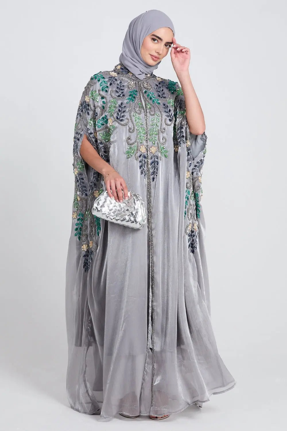 Woman wearing a gray embroidered abaya with a matching hijab on a white background