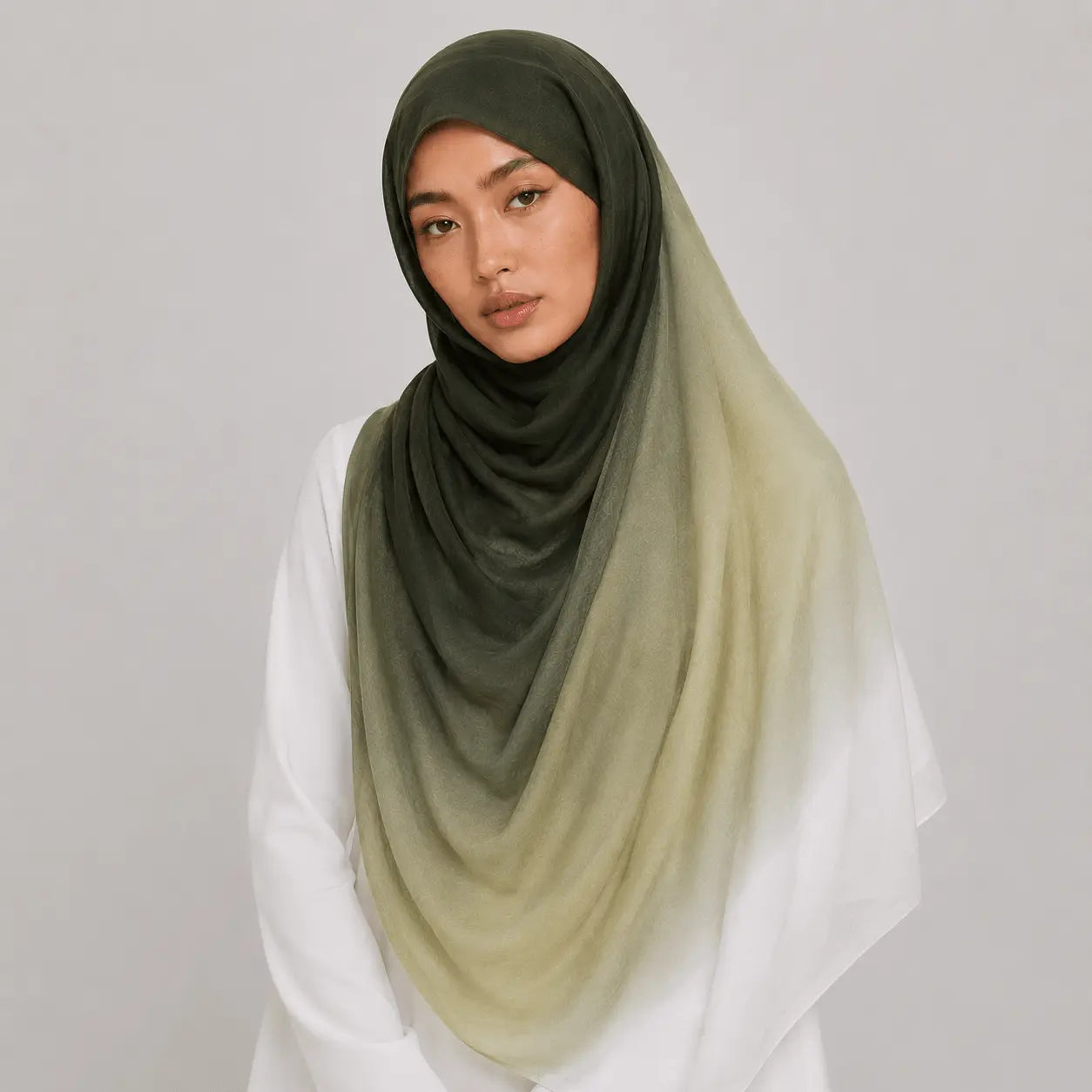 Woman wearing a green hijab with a gradient effect on a plain background
