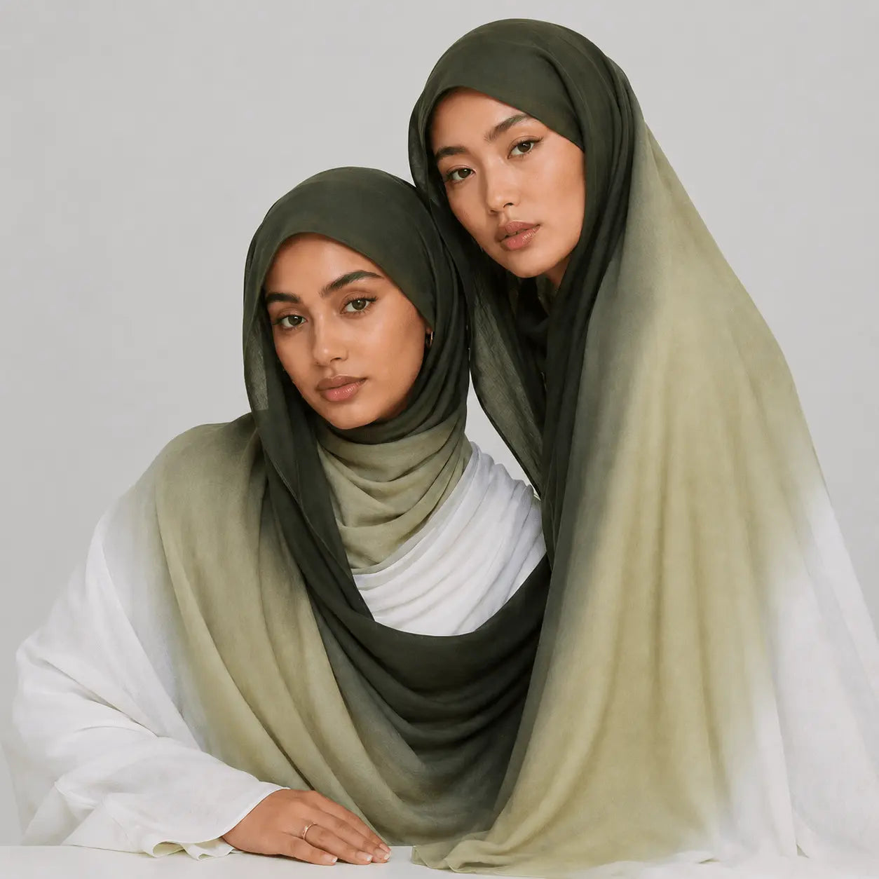 Two women wearing green hijabs on a plain background