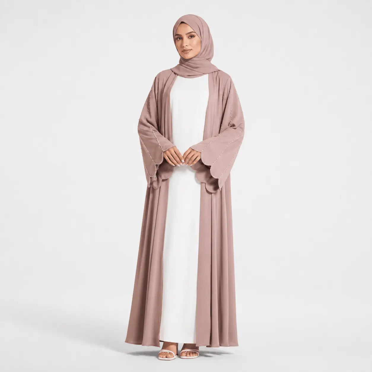 Woman wearing a long, light brown dress with a matching hijab on a white background