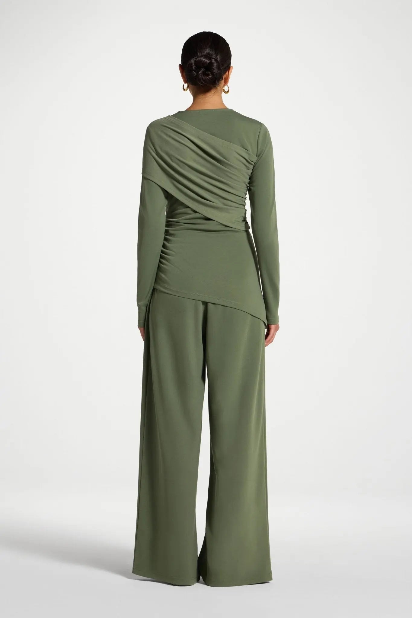 Person wearing a green outfit with a draped design on a white background