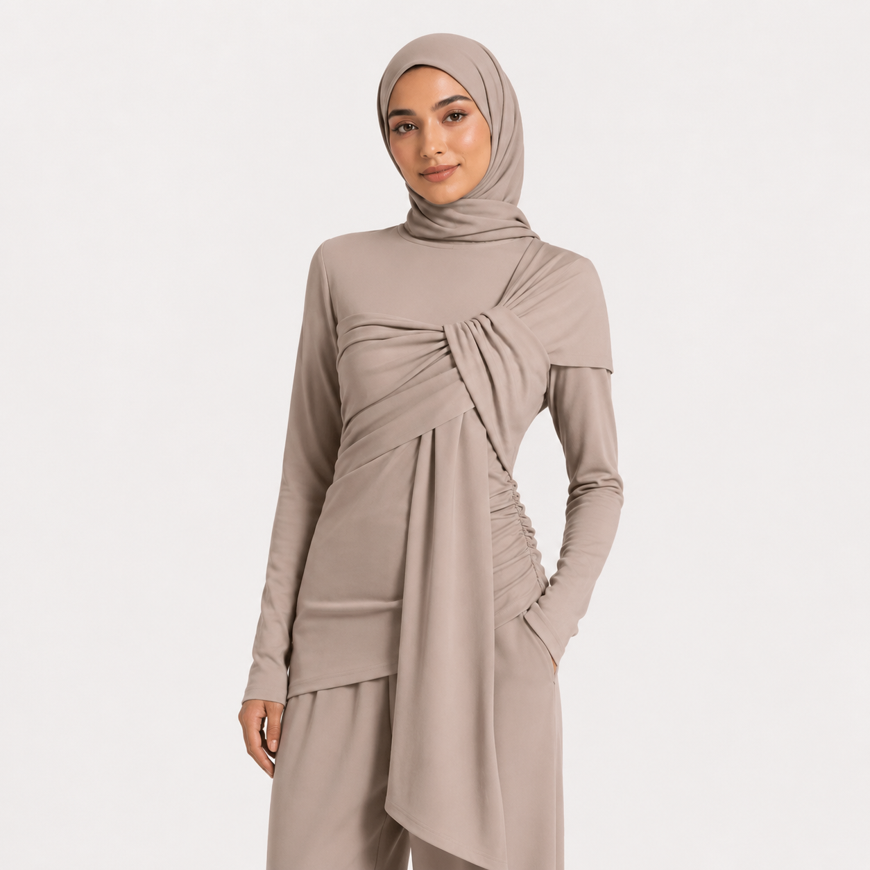 Woman wearing a beige long-sleeve top and hijab on a white background
