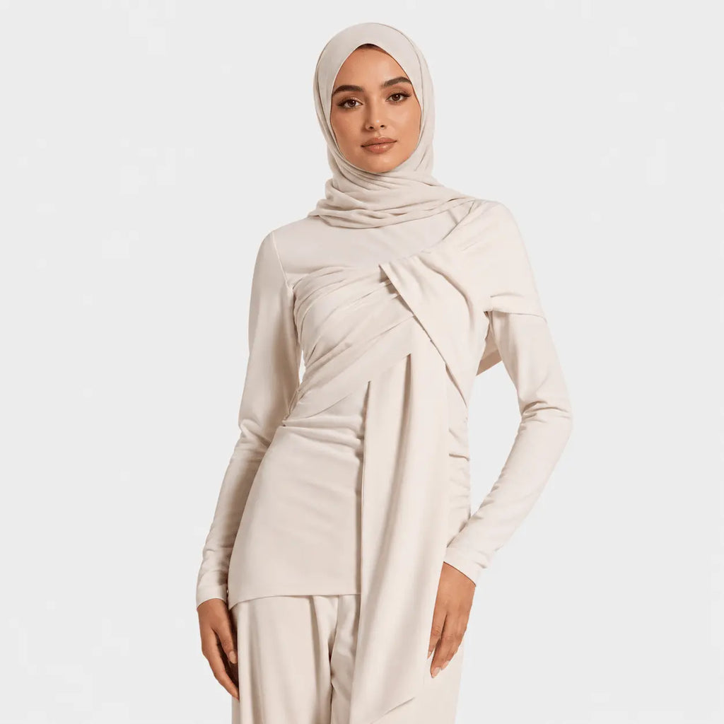 Woman wearing a beige hijab and matching outfit on a white background