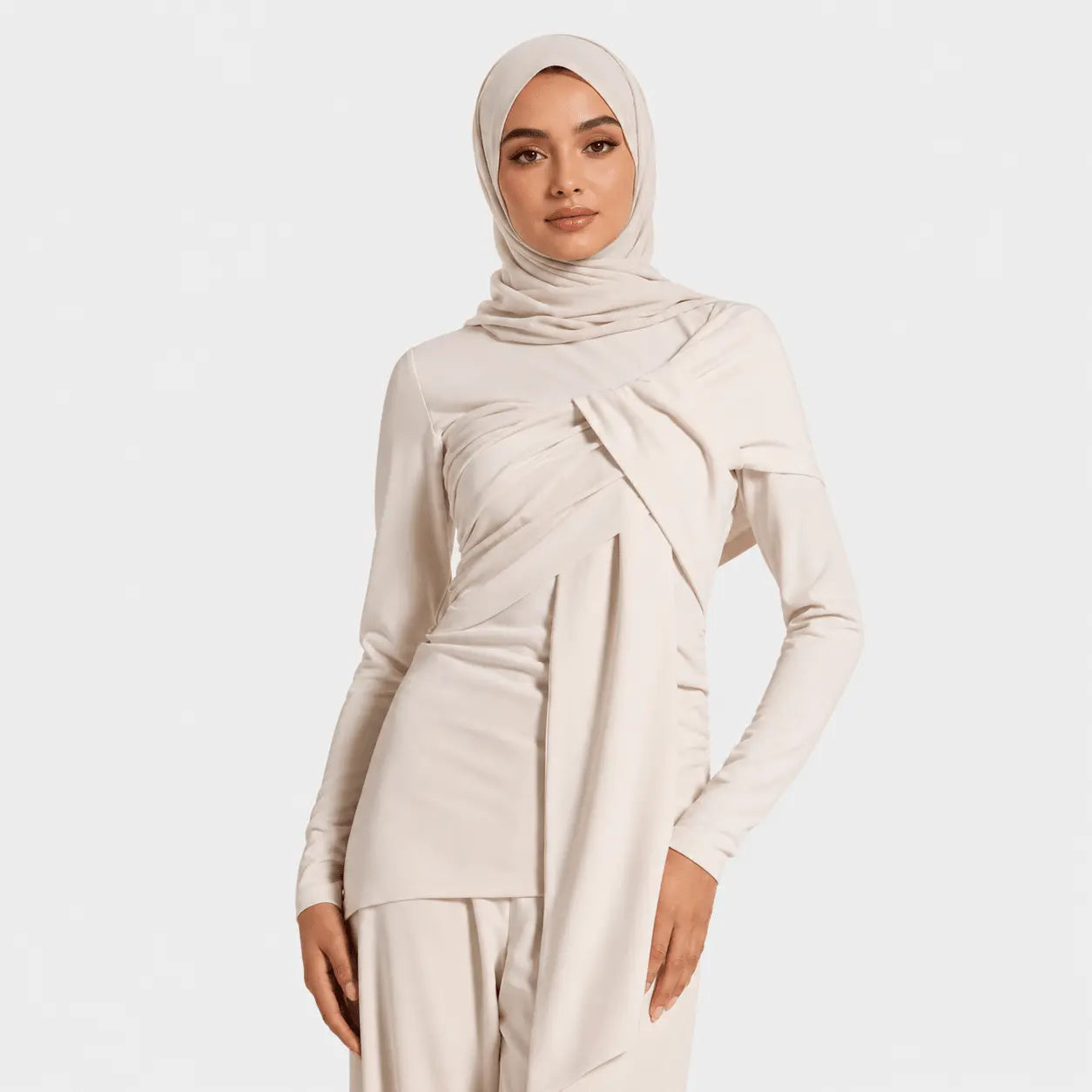 Woman wearing a beige hijab and matching outfit on a white background