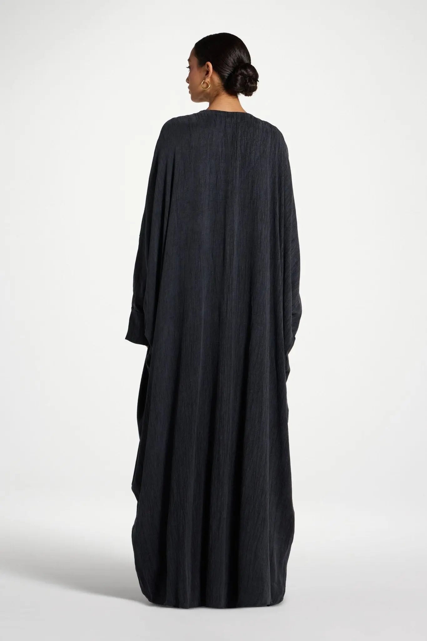 Woman wearing a long black dress against a white background