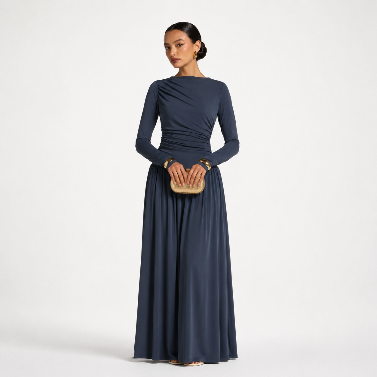Woman wearing a long navy blue dress holding a clutch on a white background