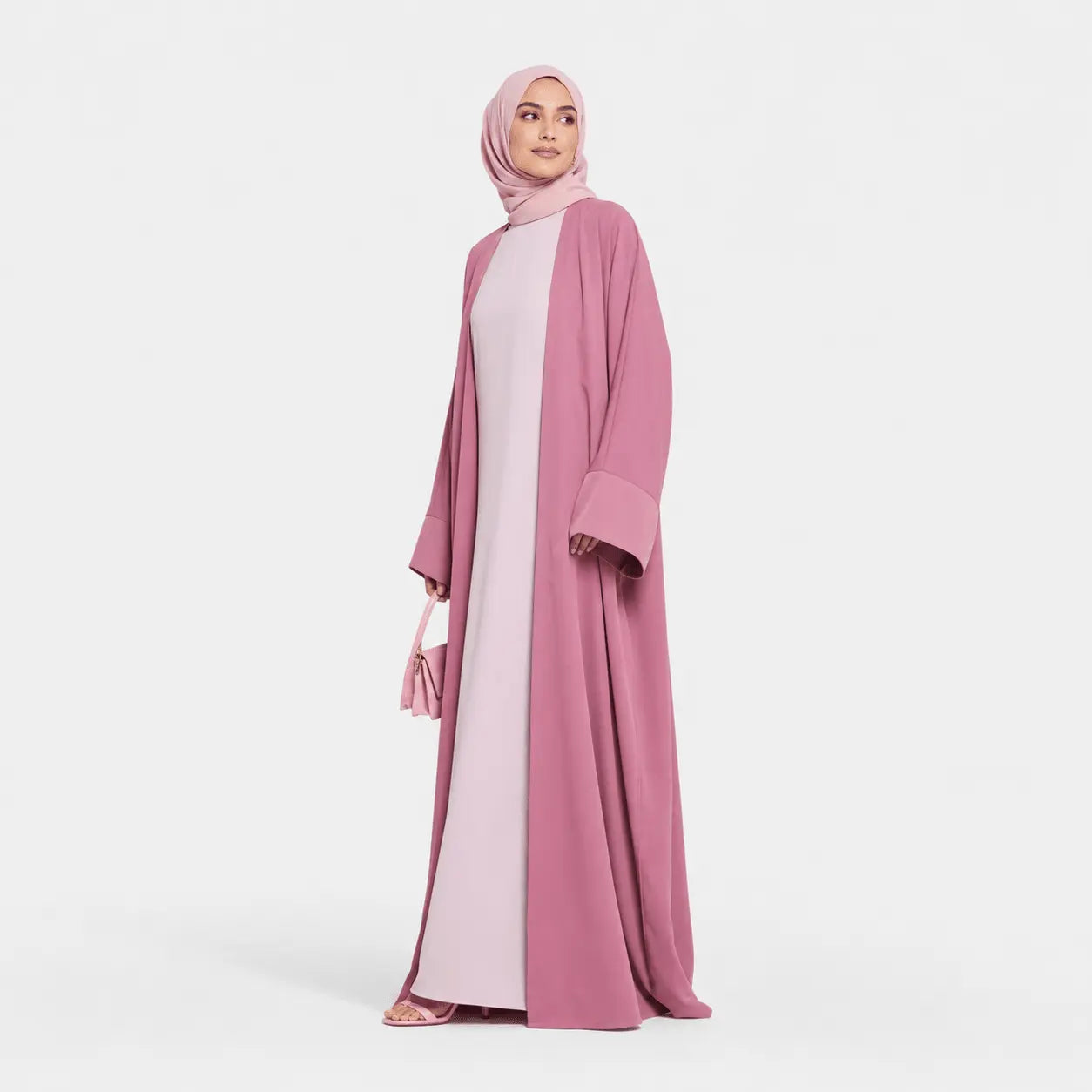 Woman wearing a pink abaya and hijab on a white background
