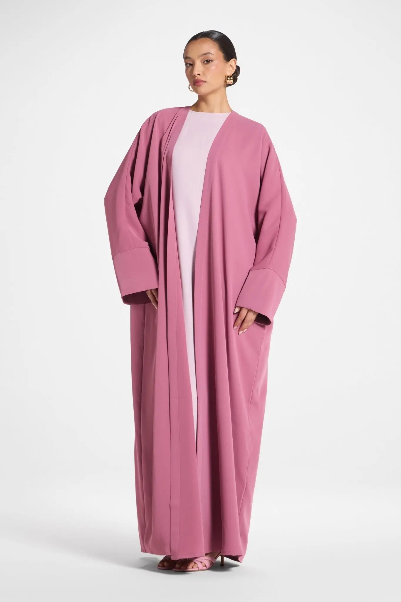 Woman wearing a pink abaya on a white background
