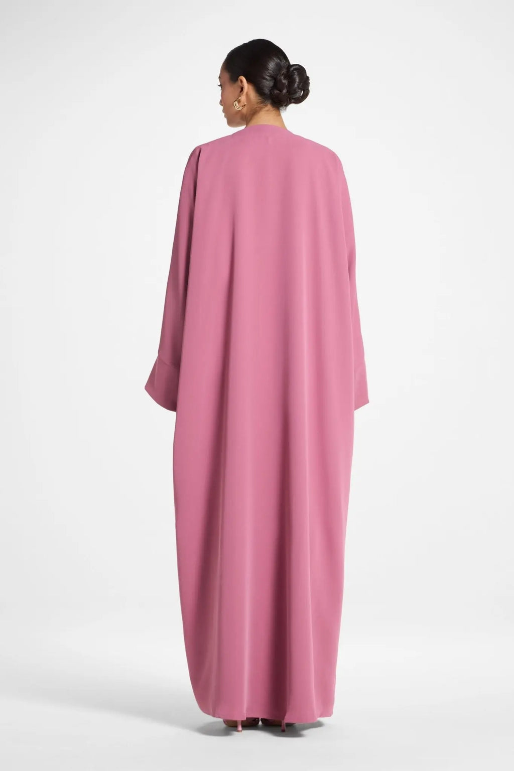 Woman wearing a pink abaya on a white background