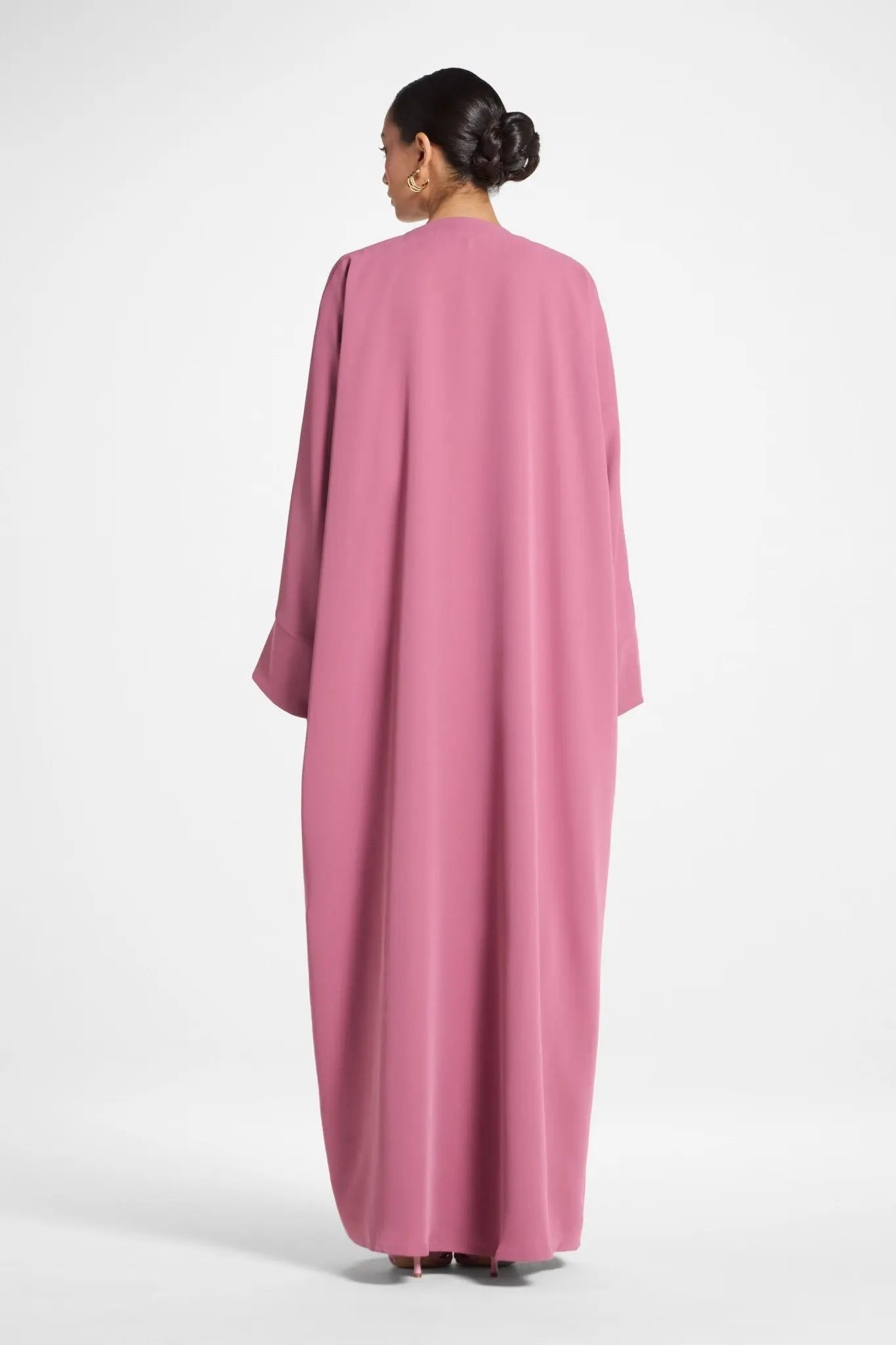 Woman wearing a pink abaya on a white background