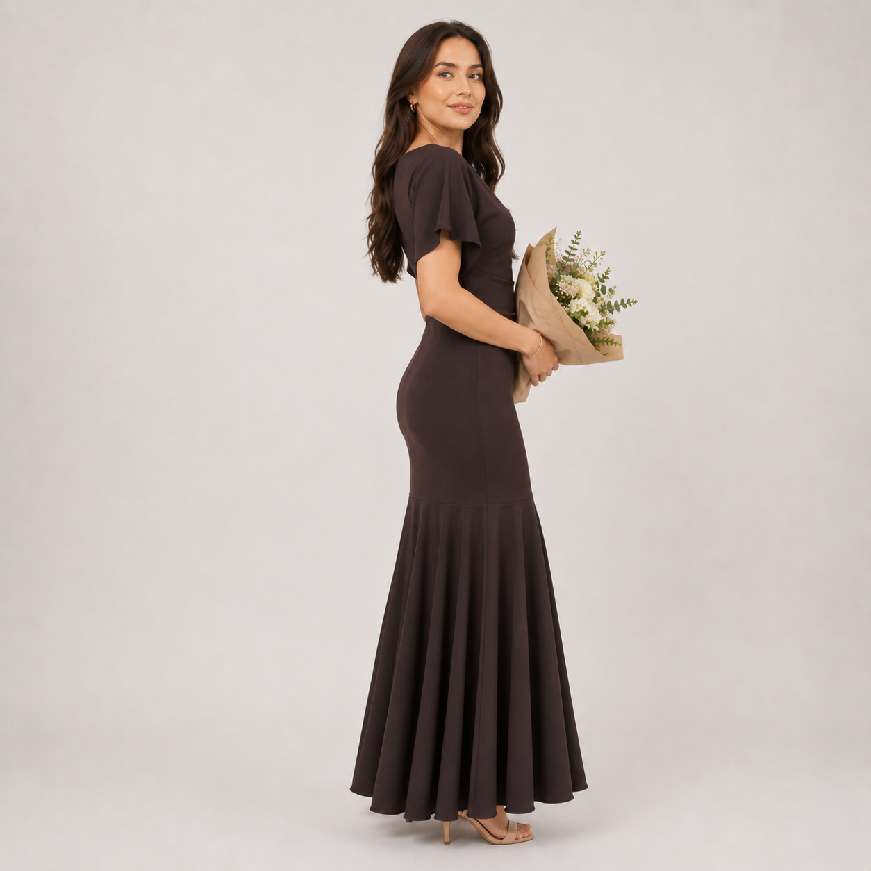 Woman wearing a brown dress holding a bouquet of flowers on a plain background