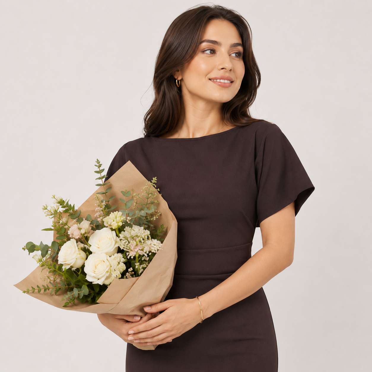 Woman holding a bouquet of flowers against a plain background