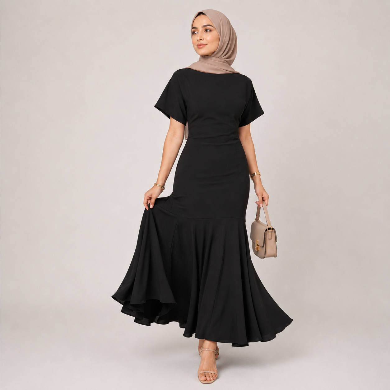 Woman wearing a black dress with a beige hijab and handbag on a light gray background
