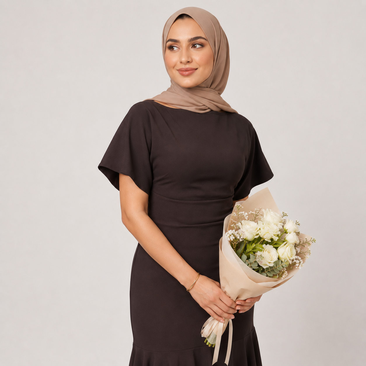 Woman in a black dress holding a bouquet of flowers against a plain background