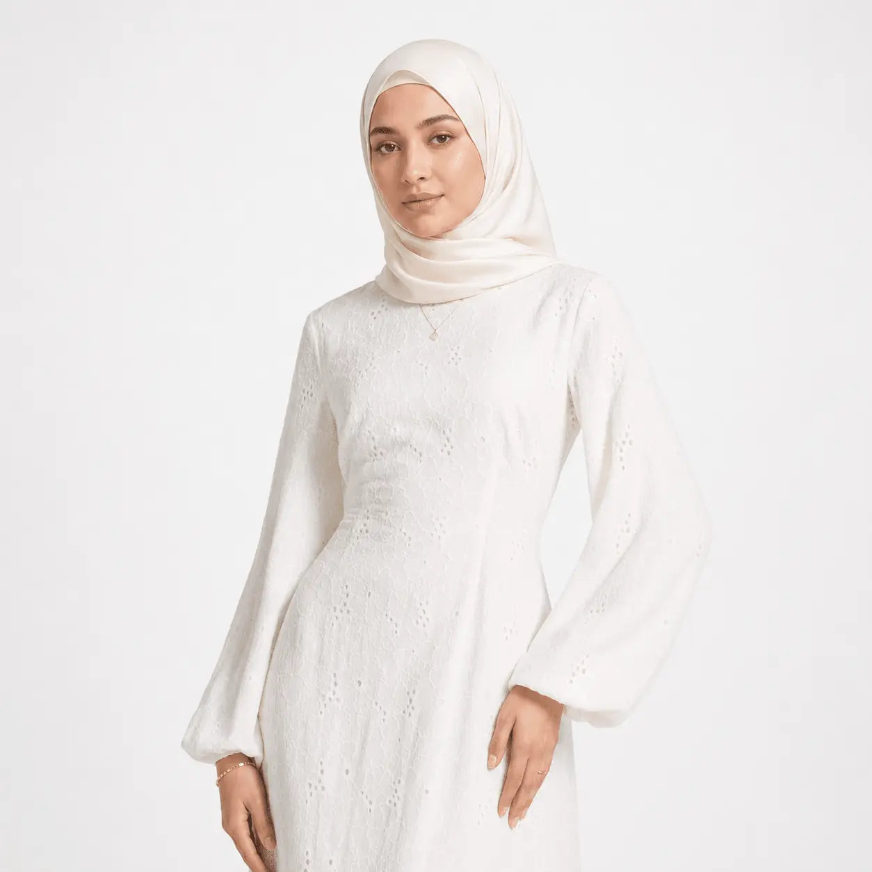 Woman in white lace modest dress with hijab, elegant long sleeves, and soft fabric texture