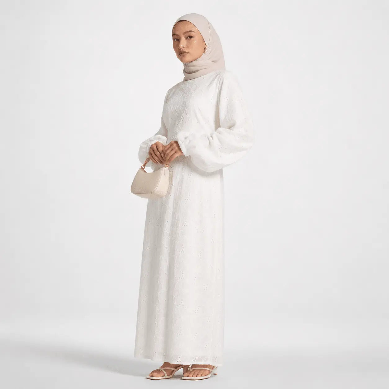 White lace abaya with puff sleeves, paired with hijab and beige handbag for modest fashion