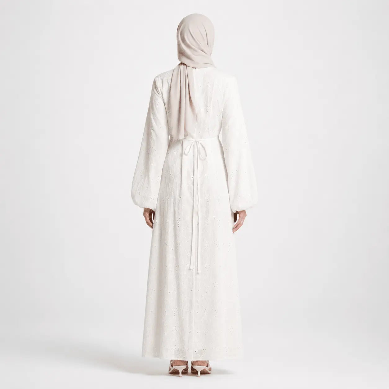 White eyelet long dress with tie waist, worn with hijab and heels, back view